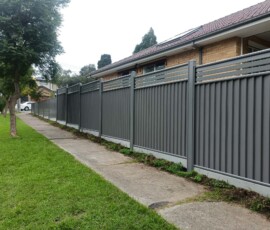Modern charcoal steel Colorbond fence running alongside a pedestrian concrete footpath